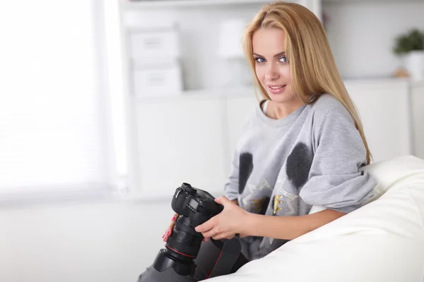 Mulher sentada em um sofá em sua casa com câmera — Fotografia de Stock