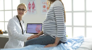 Hastanede doktorla gülümseyen güzel bir hamile kadın.