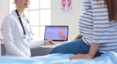 Hastanede doktorla gülümseyen güzel bir hamile kadın.