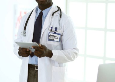 Tablet bilgisayarlı siyahi bir doktor hastanede bekliyor.