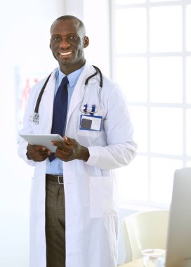 Tablet bilgisayarlı siyahi bir doktor hastanede bekliyor.
