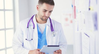 Genç ve kendinden emin erkek doktor portresi tıp ofisinde duruyor..