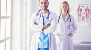 Yakışıklı doktor genç bayan doktorla konuşuyor ve ofisinde otururken notlar alıyor..