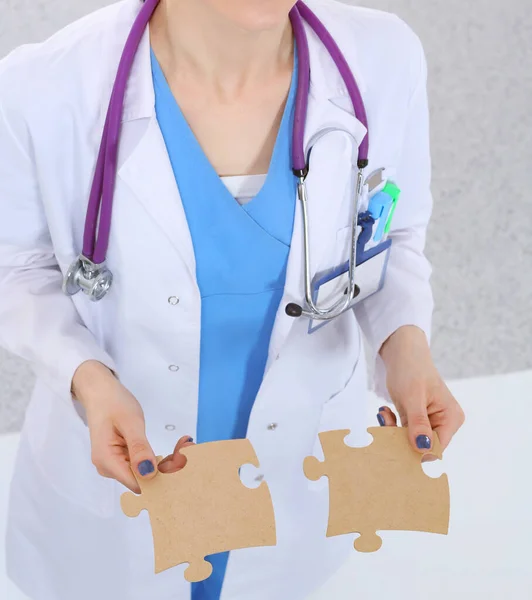 Woman doctor holding two connecting puzzle pieces — Stock Photo, Image