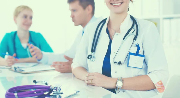 Hermosa joven sonriente doctora sentada en el escritorio — Foto de Stock