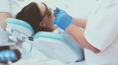 Erkek dişçi hastalarının dişleriyle uğraşıyor.