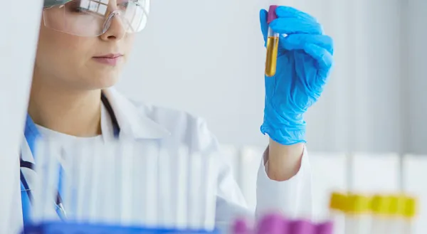 Chercheuse médicale ou scientifique ou médecin cherchant une éprouvette de solution claire dans un laboratoire — Photo