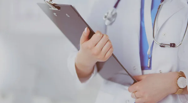 Smiling female doctor with a folder in uniform standing — Stok Foto