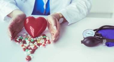 Masada kırmızı kalbi ve steteskopu olan kardiyolog.