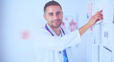 Genç ve kendinden emin erkek doktor portresi tıp ofisinde duruyor..