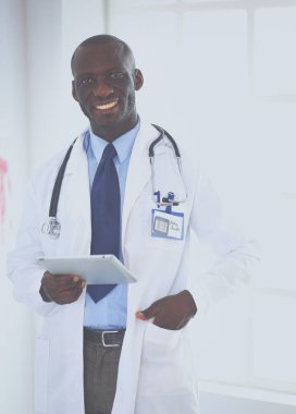 Tablet bilgisayarlı siyahi bir doktor hastanede bekliyor.
