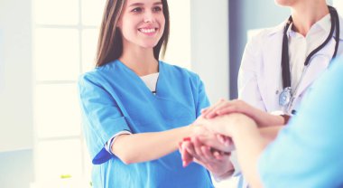 Doktorlar ve hemşireler tıbbi bir ekipte el ele tutuşuyorlar.