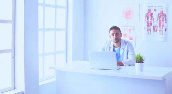 Bilgisayarlı bir erkek doktorun portresi revirde oturuyor.. — Stok fotoğraf