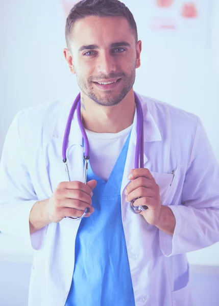 Retrato médico masculino joven y confiado de pie en el consultorio médico. —  Fotos de Stock