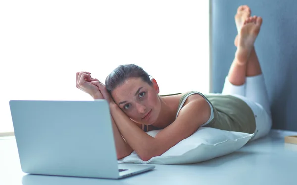 Genç bir kadın ile bir dizüstü bilgisayar yerde yatarken — Stok fotoğraf