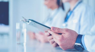 Toplantıdaki doktorlar, masanın üstünde oturuyorlar.