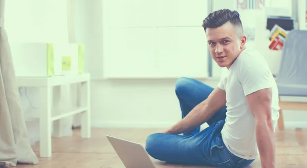 Aantrekkelijke jonge man op houten vloer liggen en het gebruik van laptop — Stockfoto