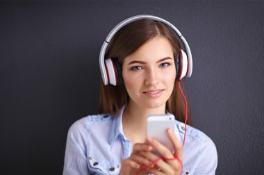gri arka plan üzerinde izole kulaklık ile gülümseyen kız