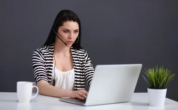 Mulher de negócios bonita trabalhando em sua mesa com fone de ouvido e laptop — Fotografia de Stock