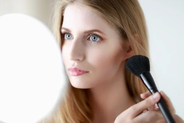 Bonita mujer aplicando maquillaje con cepillo — Foto de Stock