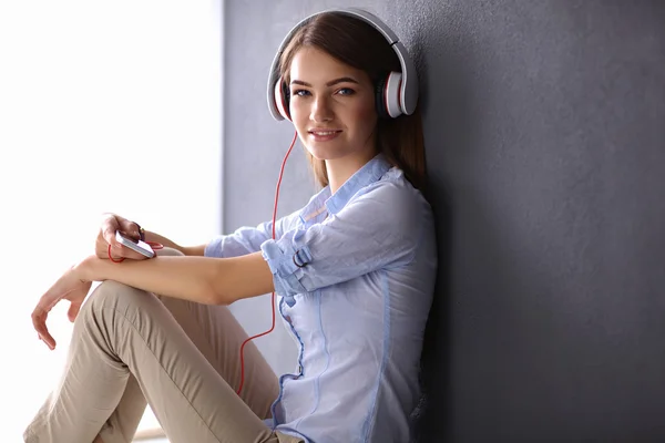 Ragazza sorridente con le cuffie sedute sul pavimento — Foto Stock