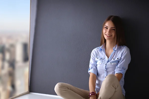 Young woman sitting on the floor near dark wall