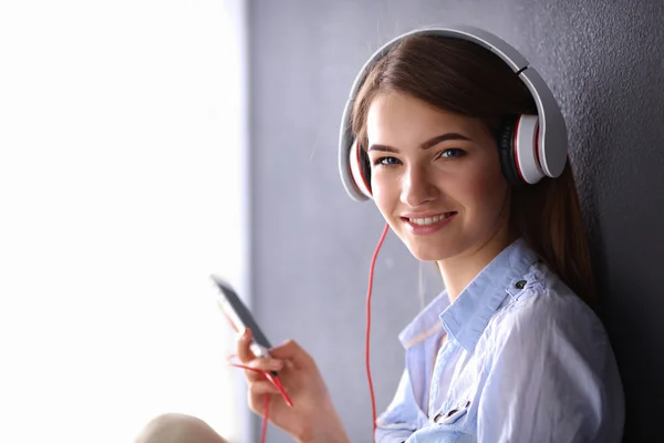 Lachende meisje met hoofdtelefoon zittend op de vloer — Stockfoto