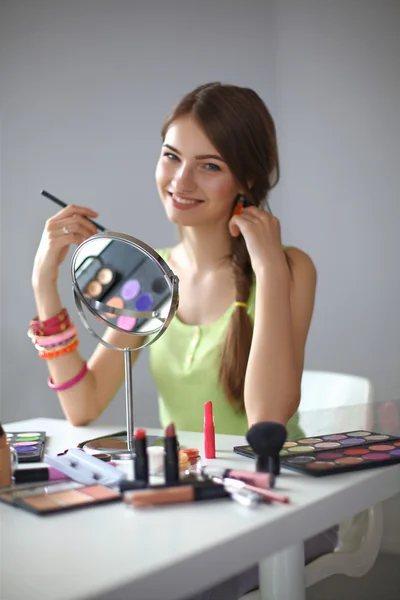 Joven hermosa mujer haciendo maquillaje cerca del espejo — Foto de Stock