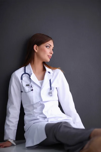 Nuori nainen lääkäri istuu lattialla — kuvapankkivalokuva