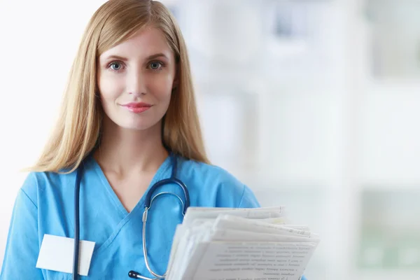 Hastane koridorunda klasörlü kadın doktor portresi.