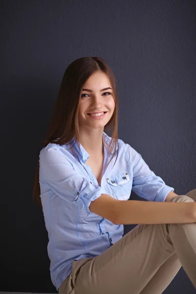 Young woman sitting on the floor isolated  dark background — Stock Photo, Image