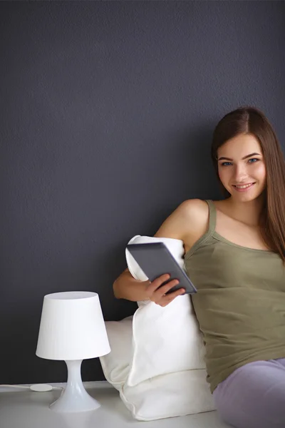 Pretty brunette woman sitting on the floor with a pillow and pl — Stock Photo, Image