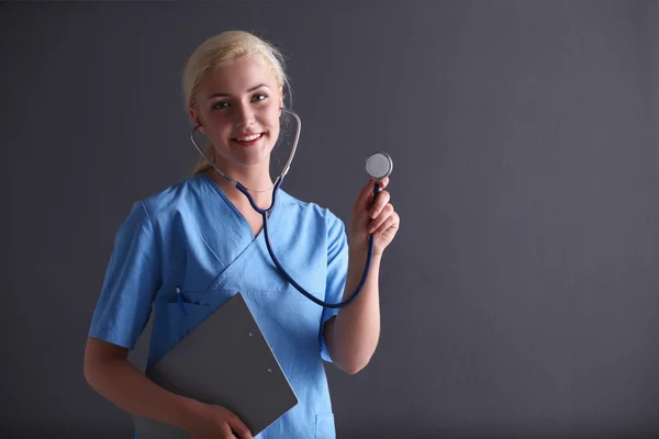 Médica com um estetoscópio ouvindo, isolada em ba cinza — Fotografia de Stock