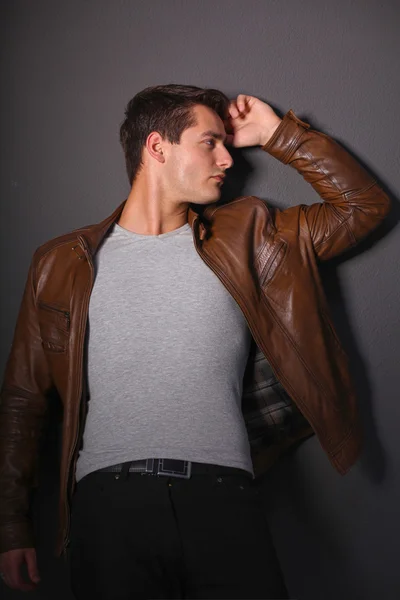 Homem posando em jaqueta de couro perto da parede — Fotografia de Stock