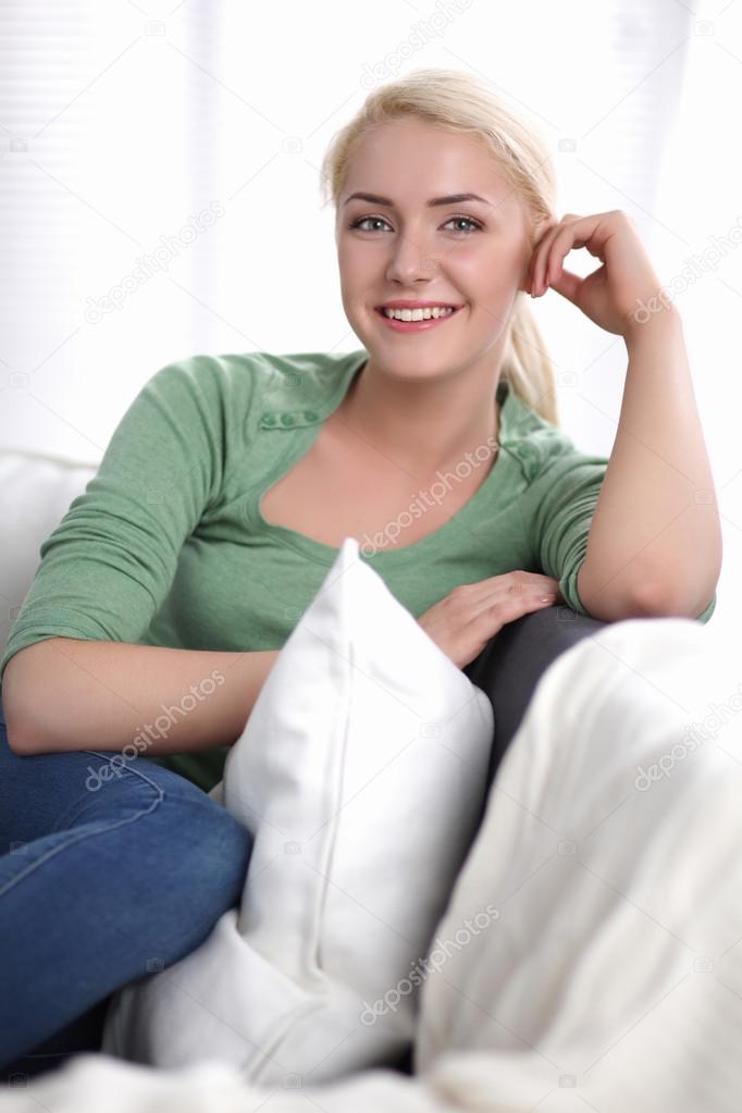 Beautiful smile young woman with white pillow sitting on the sofa