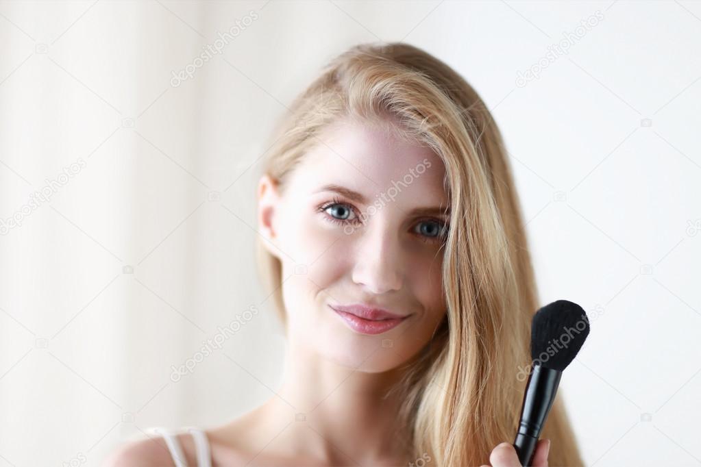 Pretty woman applying make up with brush