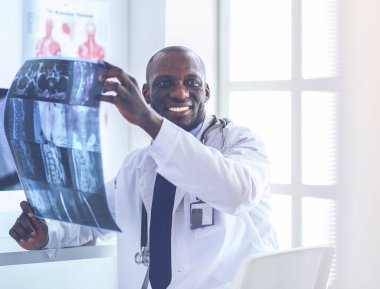 Genç Afrikalı doktor portresi hastaların röntgenlerini tutuyor.