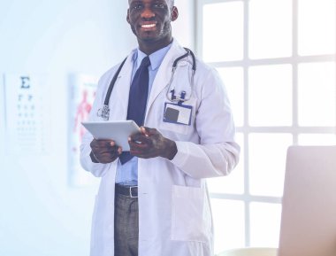 Tablet bilgisayarlı siyahi bir doktor hastanede bekliyor.