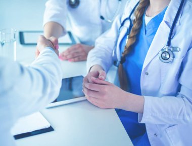 Doktor beyaz arka planda izole edilmiş bir hastayla el sıkışıyor.