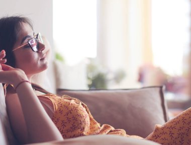 Evdeki modern bir kanepede oturan rahat kadın.