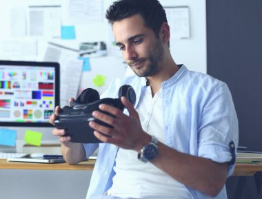 Genç erkek yazılım programcısı ofiste üç boyutlu sanal gerçeklik gözlükleriyle yeni bir uygulama test ediyor.