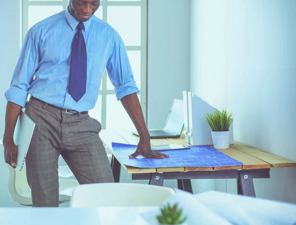 Arquiteto afro-americano trabalhando com computador e plantas no escritório — Fotografia de Stock