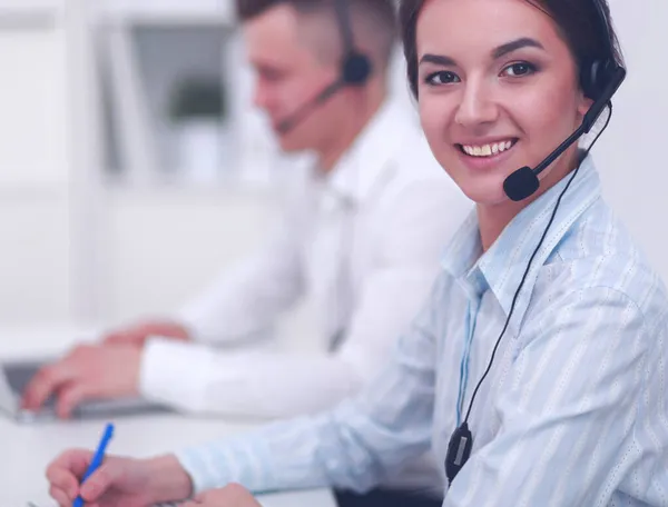 Mujer de negocios con auriculares sonriendo a la cámara en el centro de llamadas — Foto de Stock