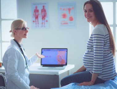 Hastanede doktorla gülümseyen güzel bir hamile kadın.