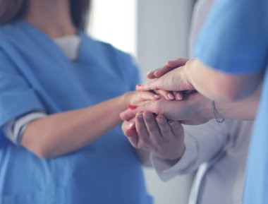 Doktorlar ve hemşireler tıbbi bir ekipte el ele tutuşuyorlar.