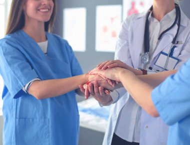 Doktorlar ve hemşireler tıbbi bir ekipte el ele tutuşuyorlar.