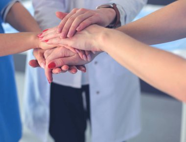 Doktorlar ve hemşireler tıbbi bir ekipte el ele tutuşuyorlar.