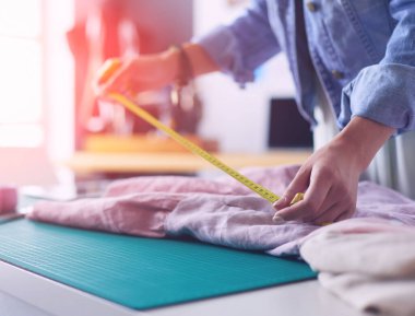 Moda tasarımcısı kadın stüdyoda tasarımları üzerinde çalışıyor.