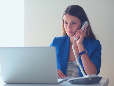 Telefon bir dizüstü bilgisayar önünde genç kadın portre