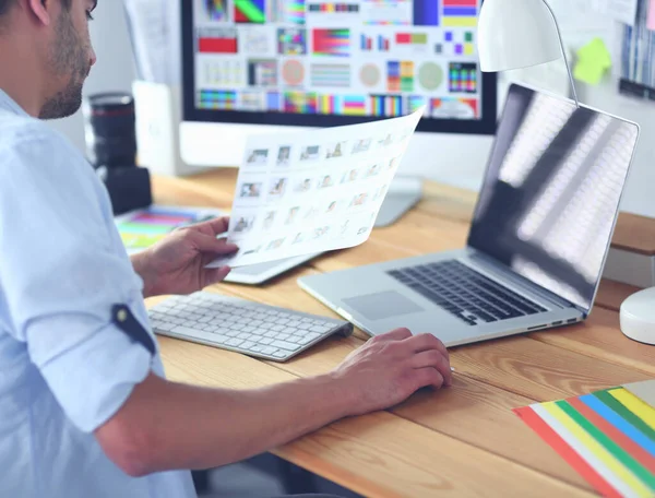 Retrato del joven diseñador sentado en el estudio gráfico frente a la computadora portátil y el ordenador mientras trabaja en línea. —  Fotos de Stock